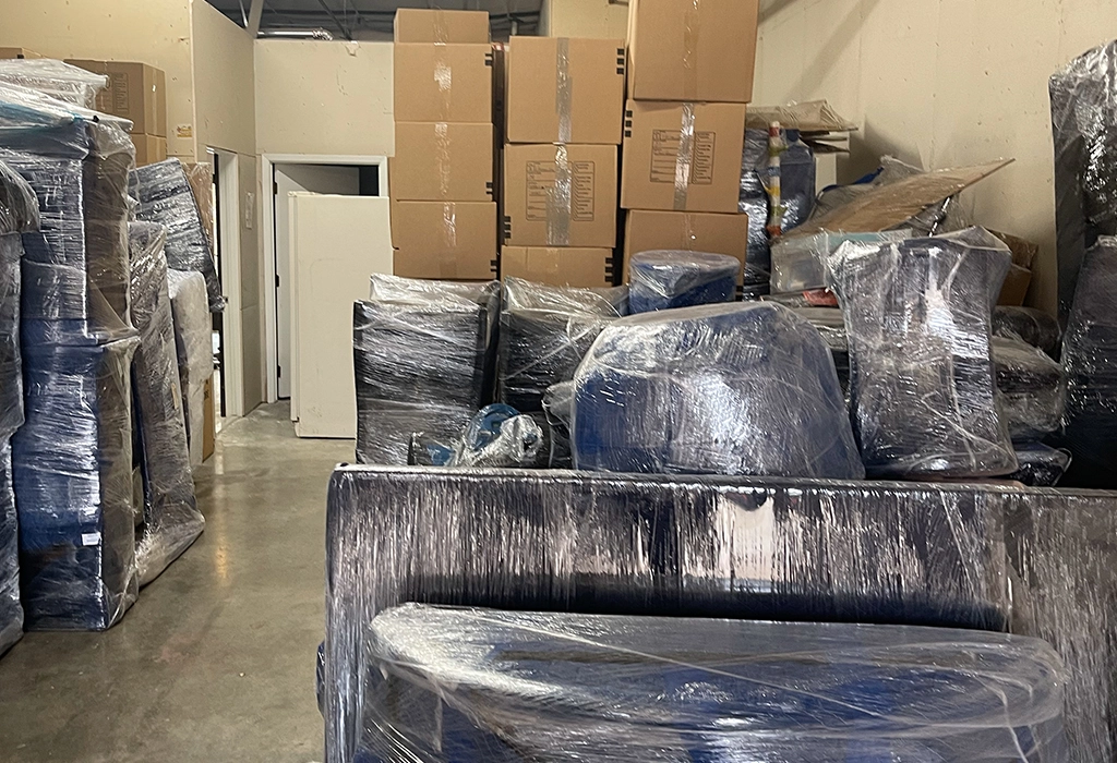 A spacious room filled with various boxes and pieces of furniture, creating a cluttered yet organized environment