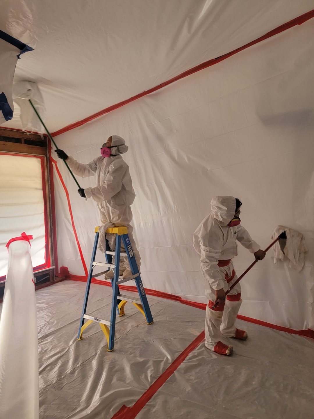 A man in a white suit and dust mask meticulously cleans a room, ensuring a safe and tidy environment